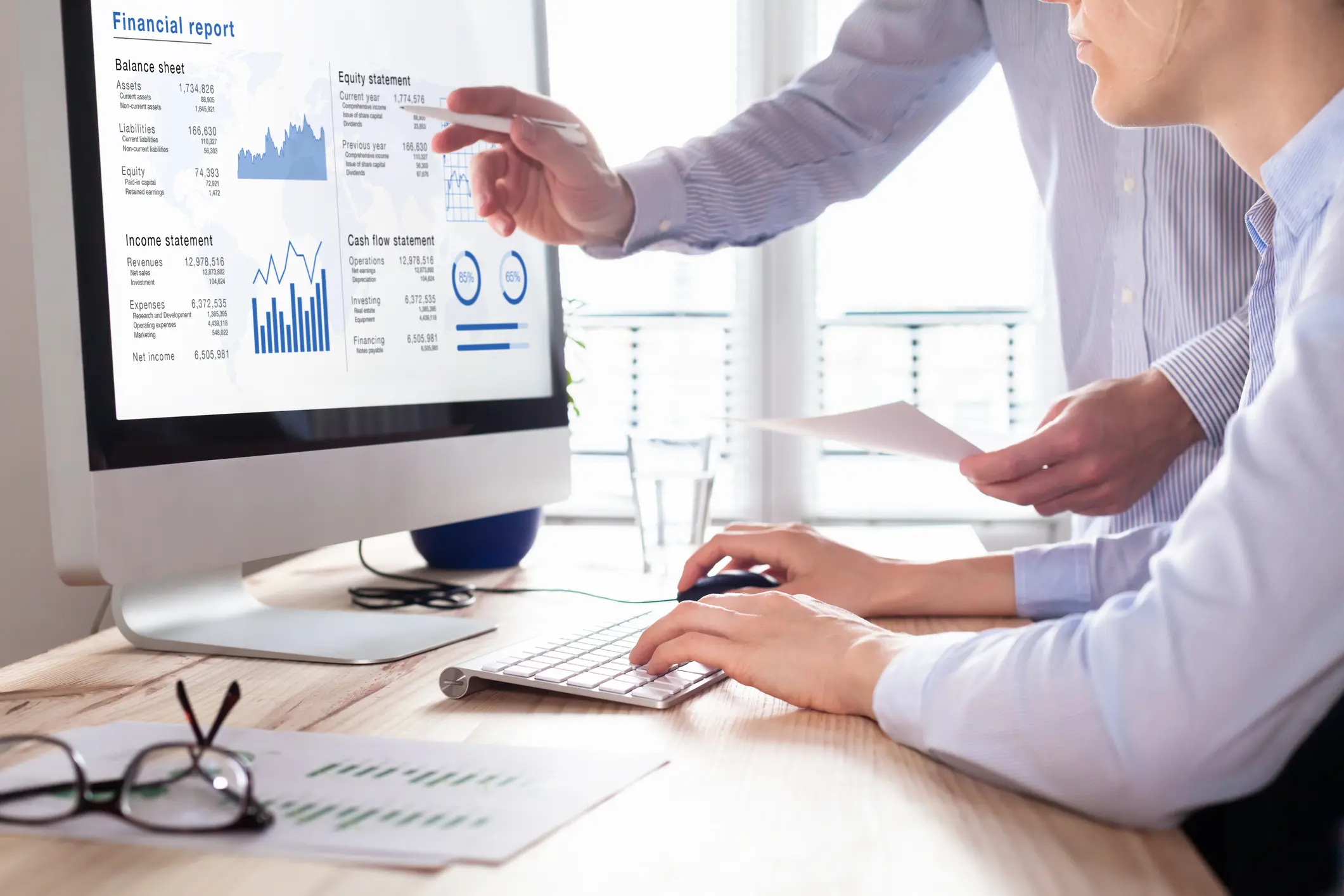 Consulting auditors auditing financial report on computer screen, business charts two people reviewing a financial report on a computer monitor