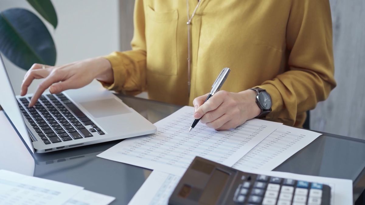 Professional business woman in yellow blouse is working on financial reports.