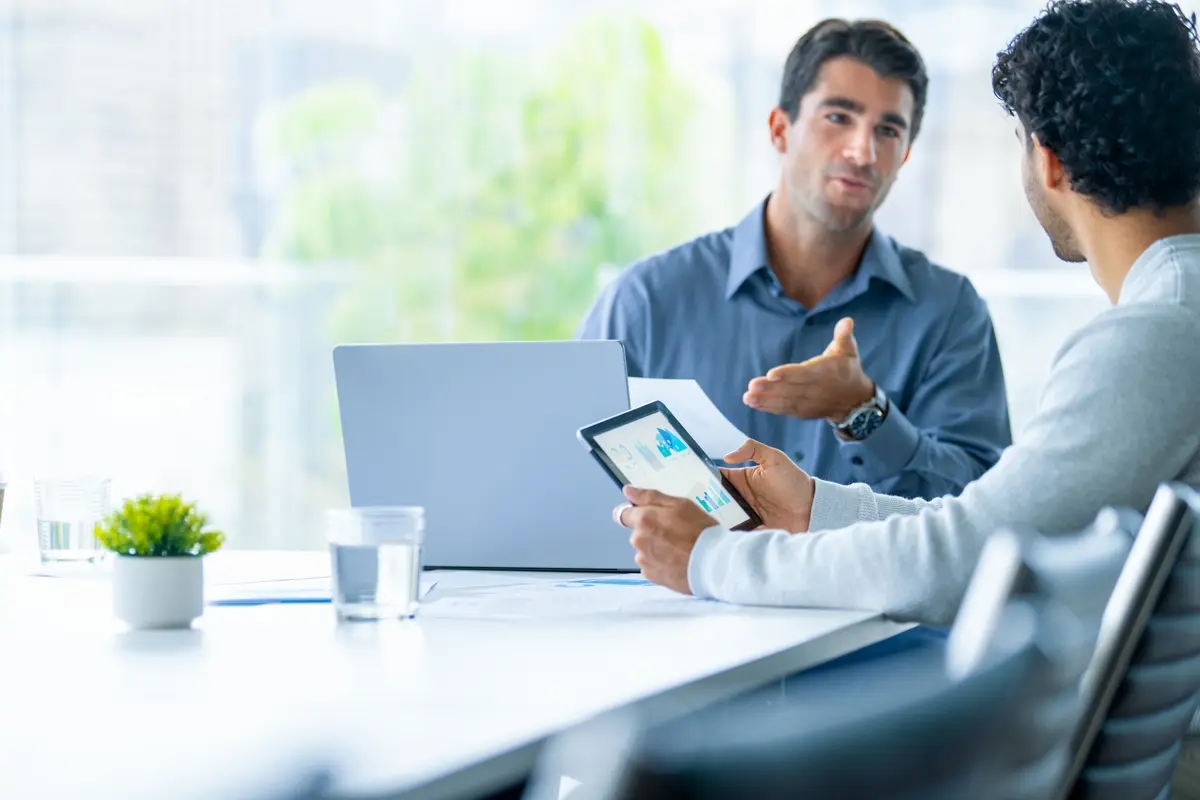 Two people working on a digital tablet and laptop computer in the office.
